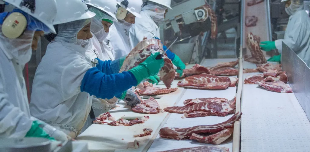 workers cutting meat at a factory