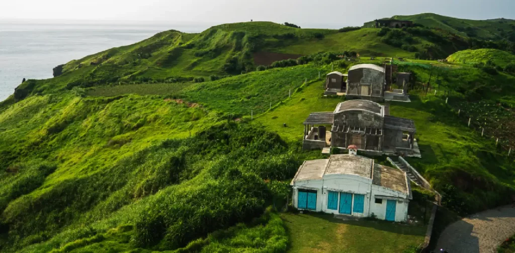 aerial view of three old buildings on the grassy hill of batanes islands in the Philippines