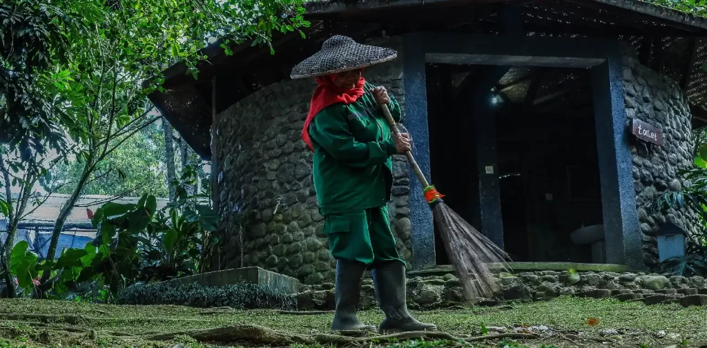 a female domestic worker sweeping a garden