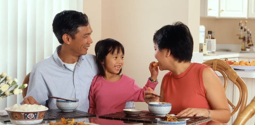 a father, daughter, and mother sitting in a dining table