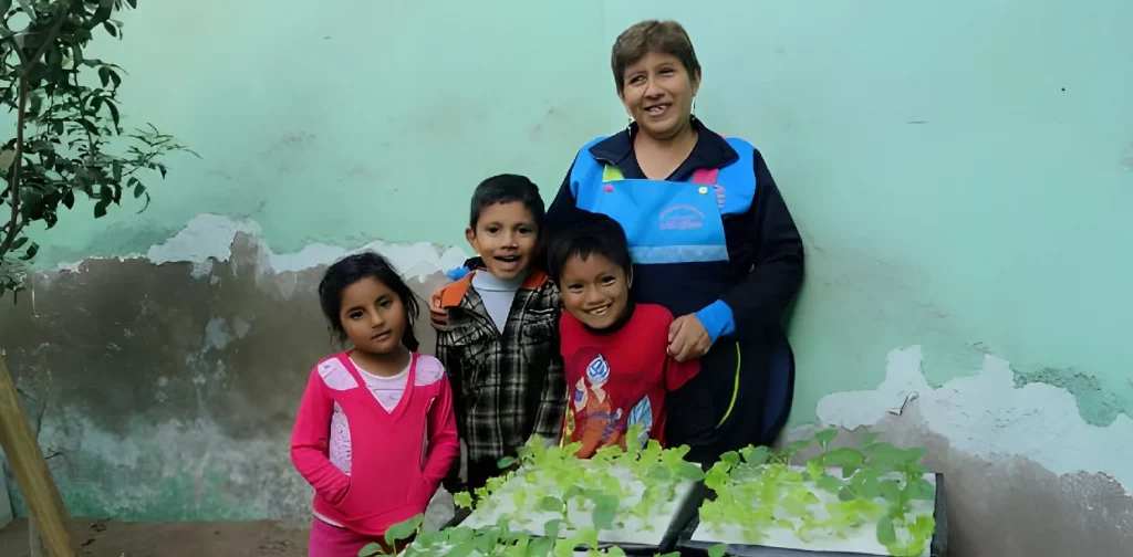 three kids with one woman standing in front of hydroponics plants