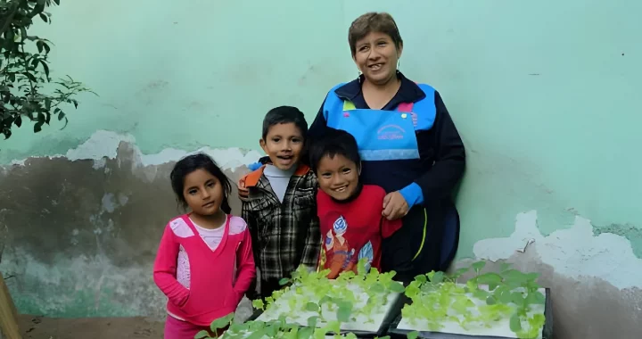 three kids with one woman standing in front of hydroponics plants