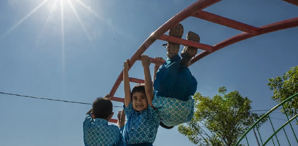 three boys playing in on a monkey bar