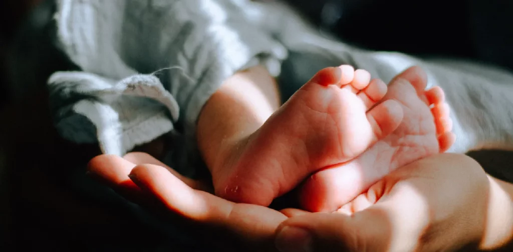 a mother’s hand holding baby feet
