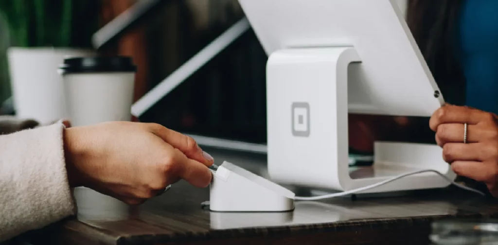 two people doing transaction with a white monitor between them