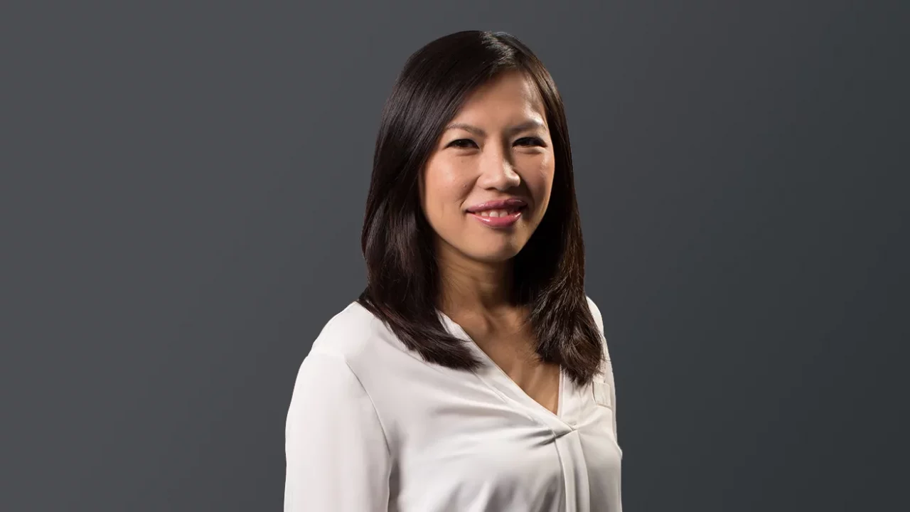 a photo of Yap Mun Ching, a woman with long hair in a white attire against a grey backdrop