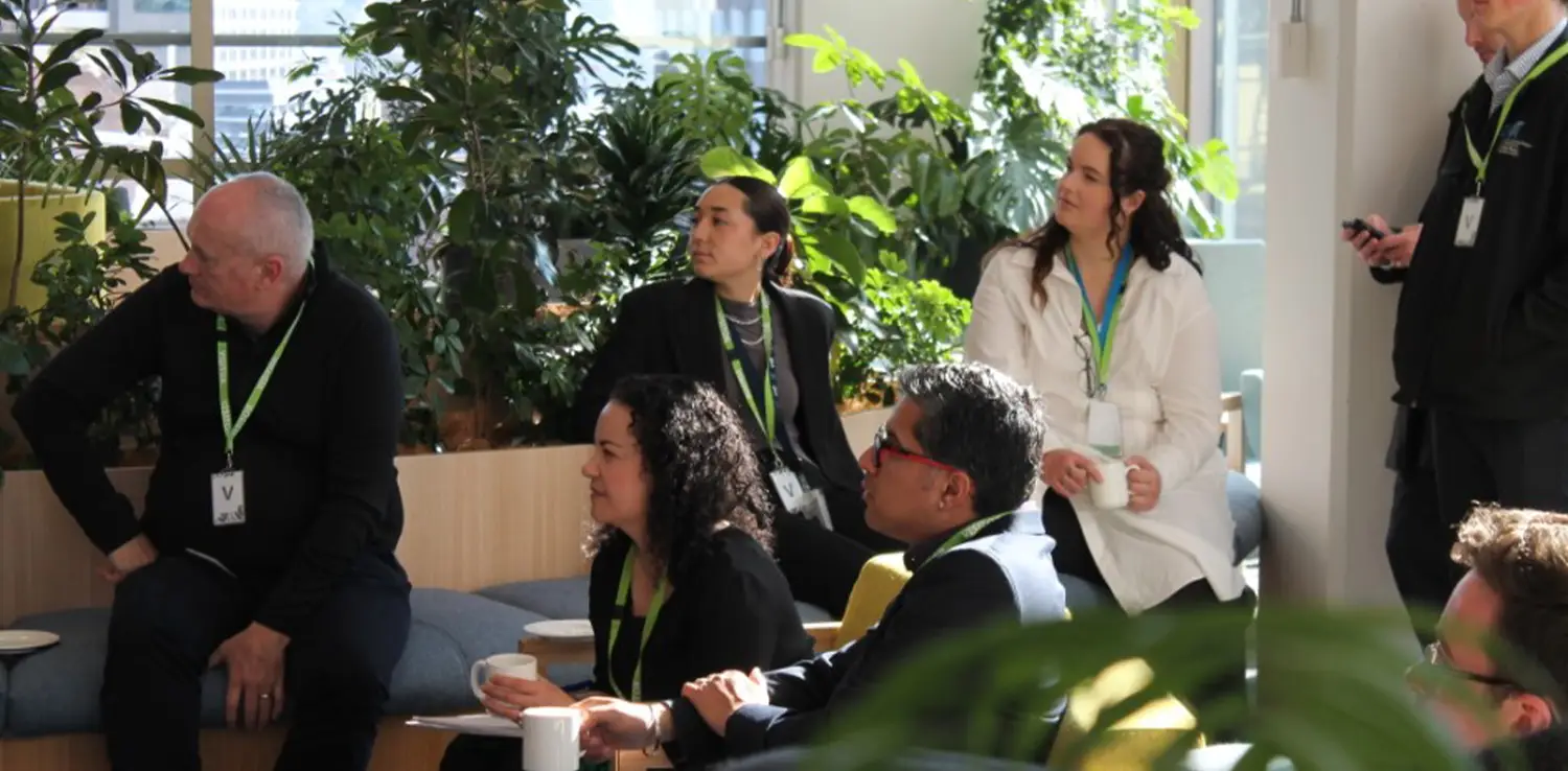 men and women in a discussion in a sunlit room with plants