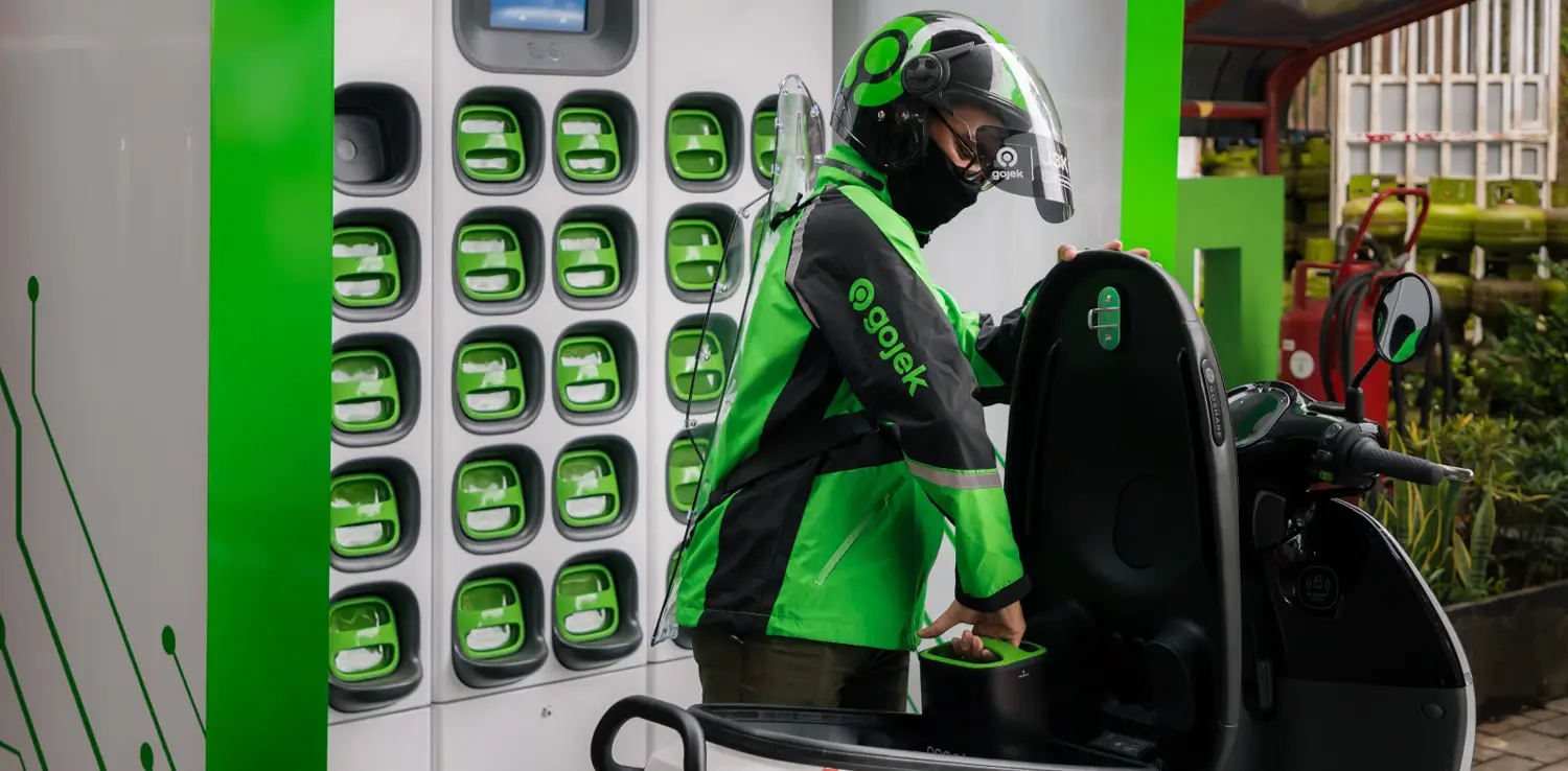 an online motor-taxi driver changing the battery of his electric motorcycle