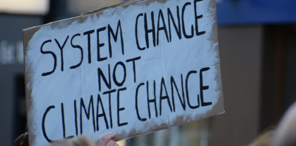 a hand holding a banner that says ‘system change not climate change’