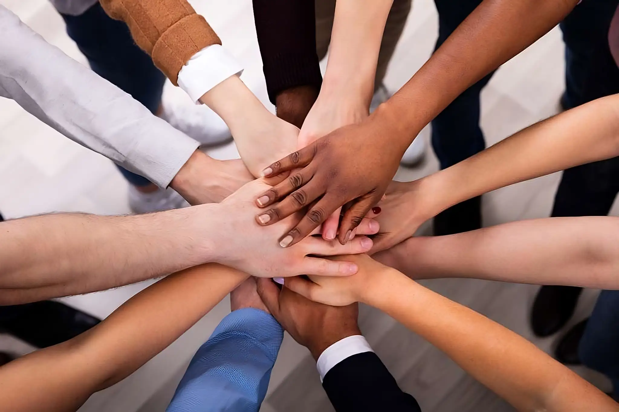 Diverse people stack their hands together