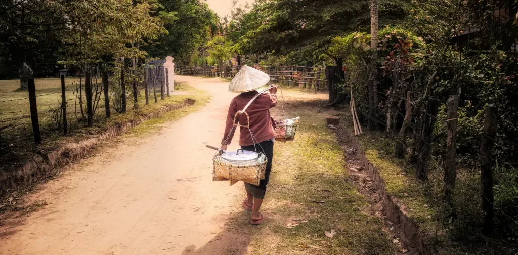 a woman walking down the road carrying two baskets