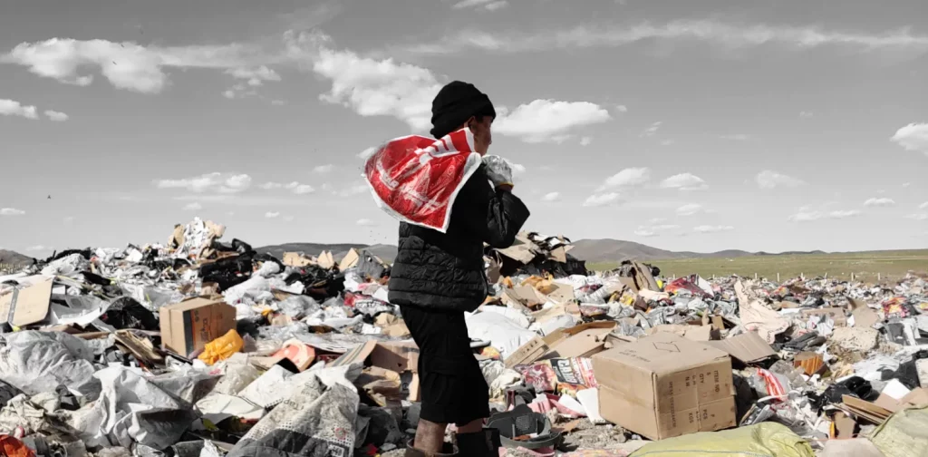 a child carrying a plastic bag scavenging at a dumpsite