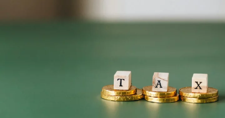 block letters forming the word ‘tax’ sitting on top of gold coins