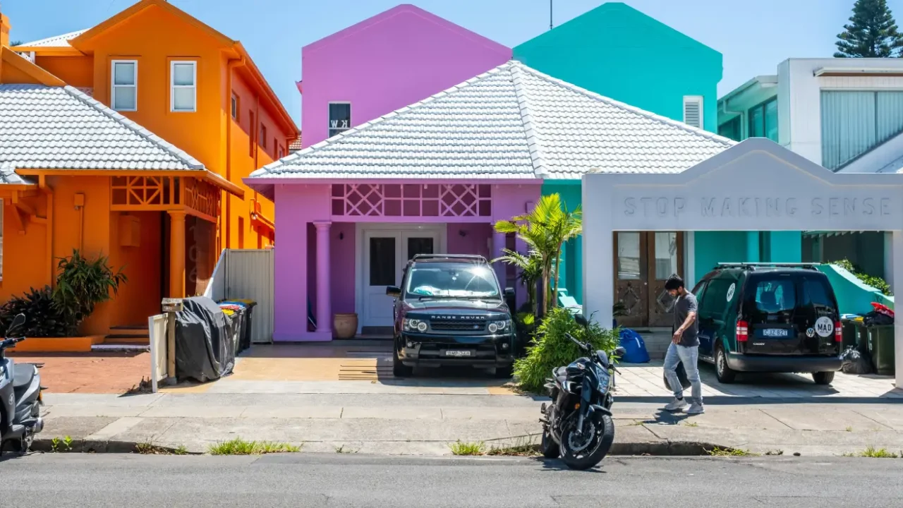 a man walking in front of three colorful houses