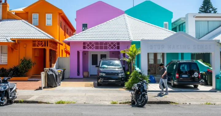 a man walking in front of three colorful houses