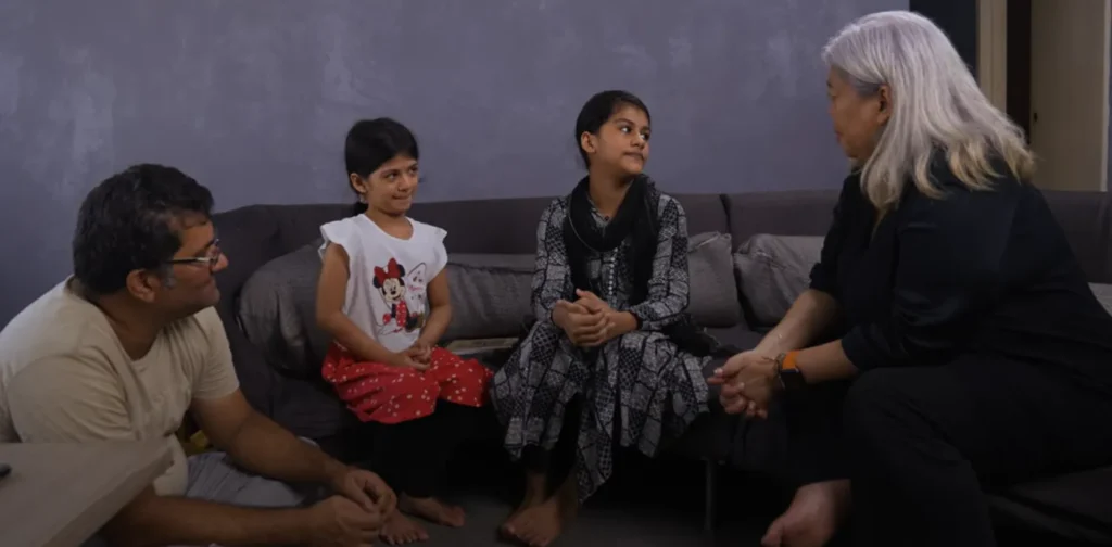 a man, two girls, and a woman sitting in a living room