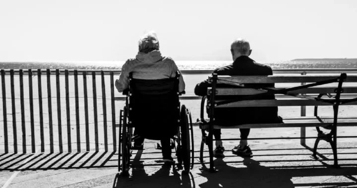 two elderly people sitting with the back facing camera