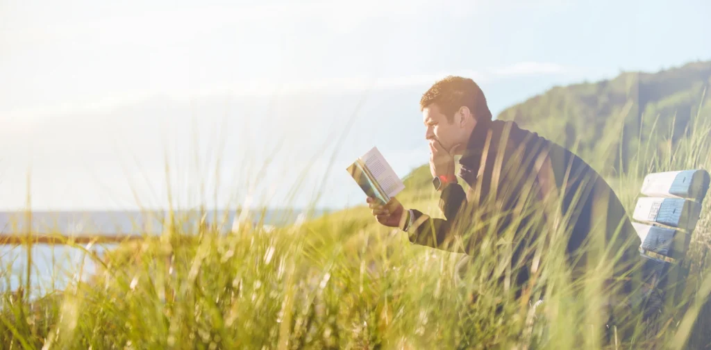 a man reading a book in an open field