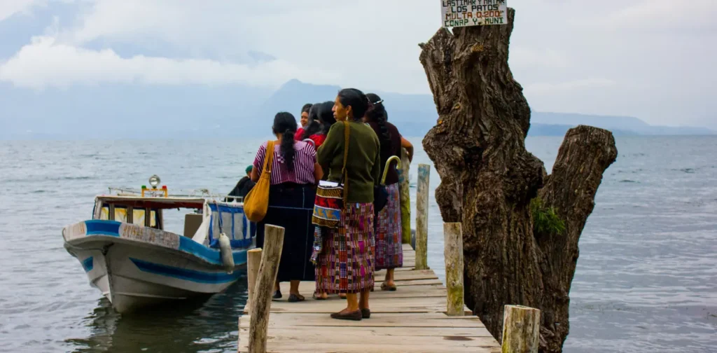 a group of women standing by the lake with a boat by the side