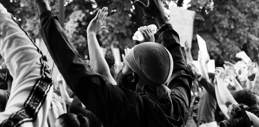 Man wearing black suit in a crowd with his hands on the air