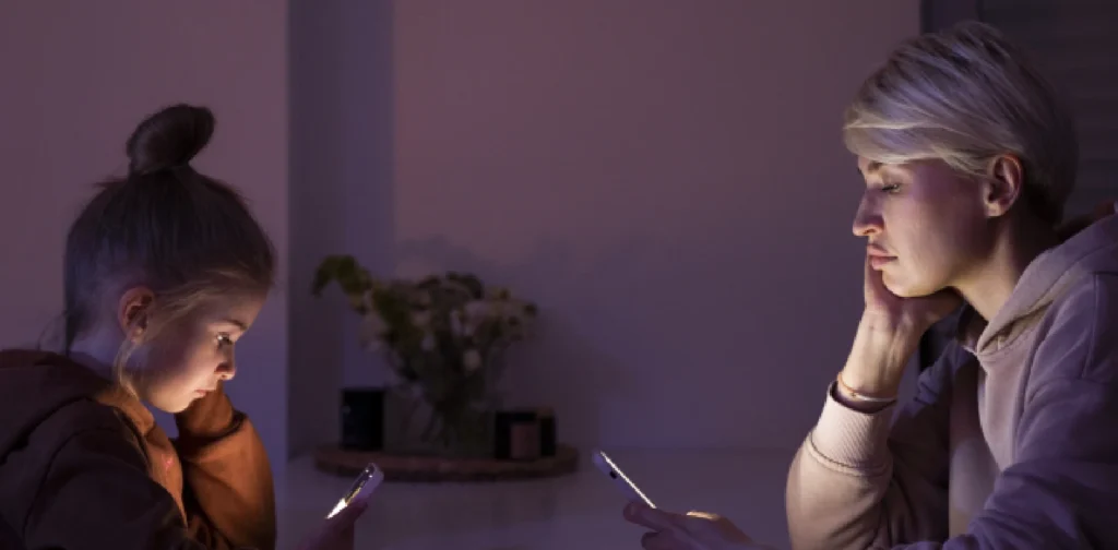 a young girl and a woman looking at their smartphones