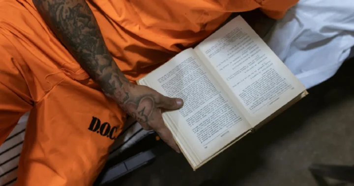 Male inmate reading a book on bed