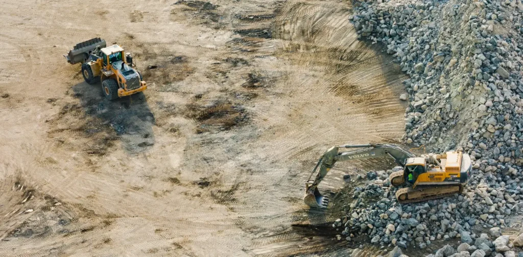 three yellow excavators gathering sand and rocks