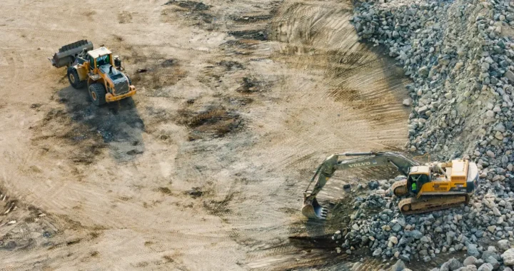 three yellow excavators gathering sand and rocks