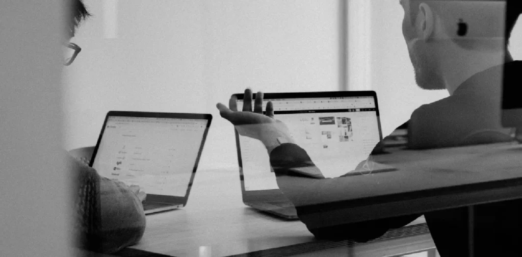 a grayscale photo of two people in the middle of a meeting