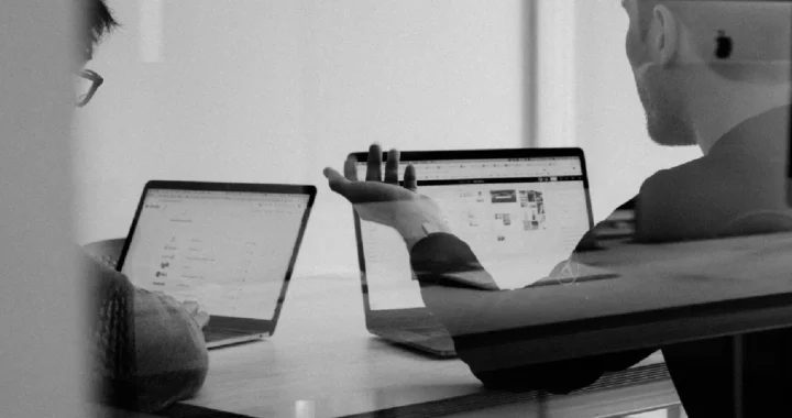 a grayscale photo of two people in the middle of a meeting