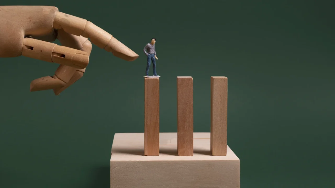 a small wooden figure of a man standing on a wooden block with a hand threatening to push him