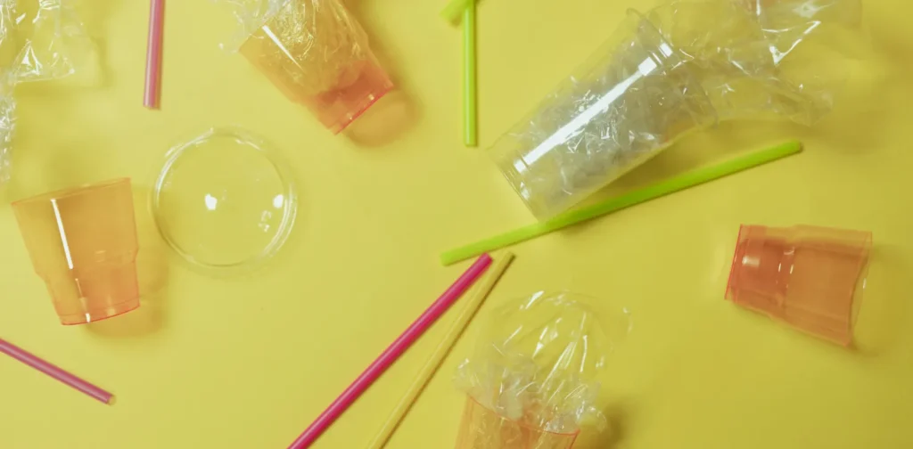 plastic cups and straws on flat background