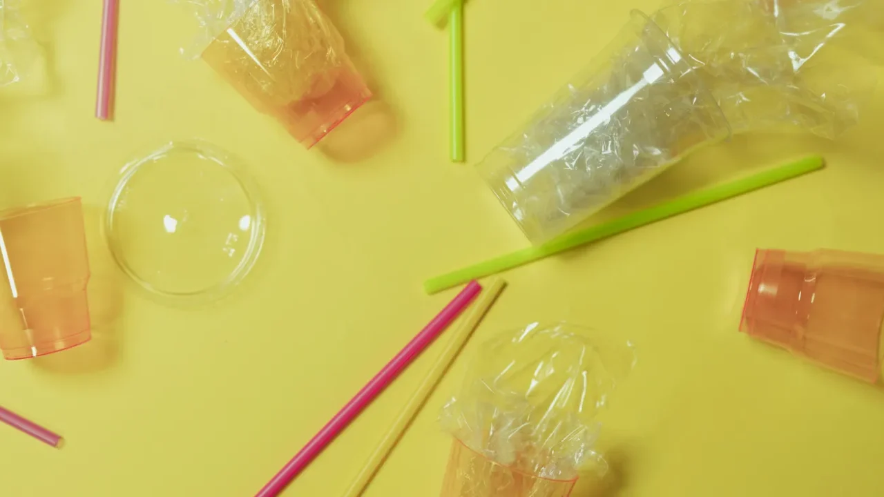 plastic cups and straws on flat background