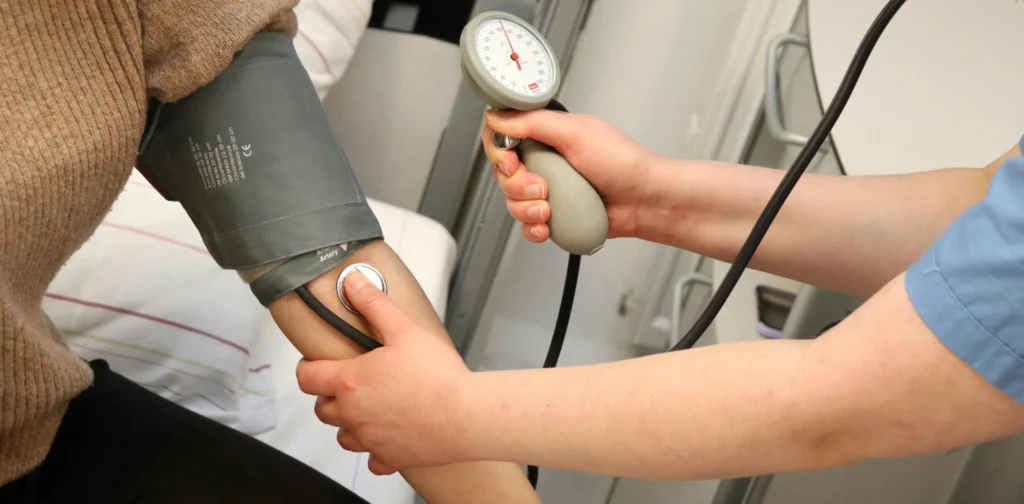 person undergoing blood pressure check with a device on their arm