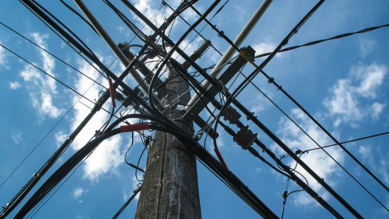 a low angle photo of electric post with a bunch of cables