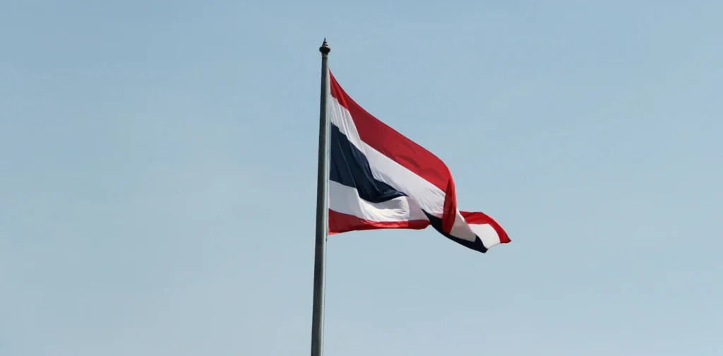 a Thailand flag on a pole against blue sky