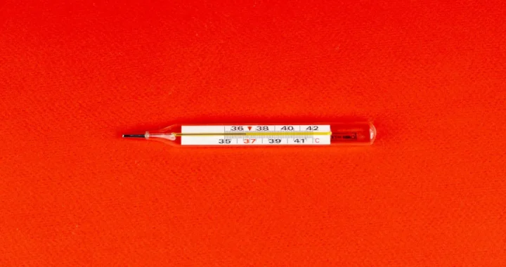 a thermometer placed against a red backdrop