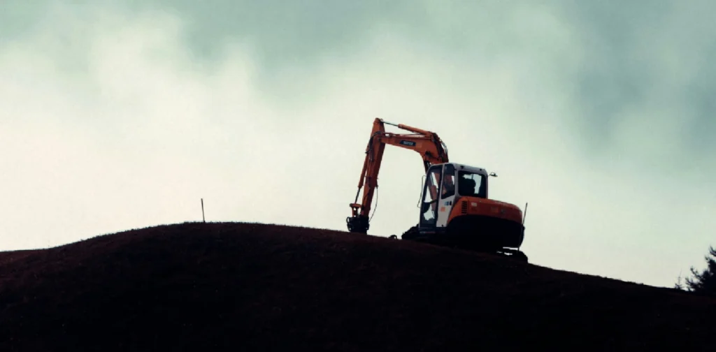 a silhouette of an excavator on a hill