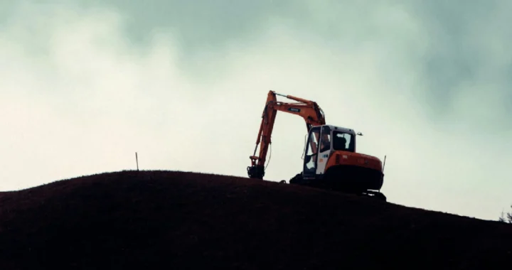 a silhouette of an excavator on a hill