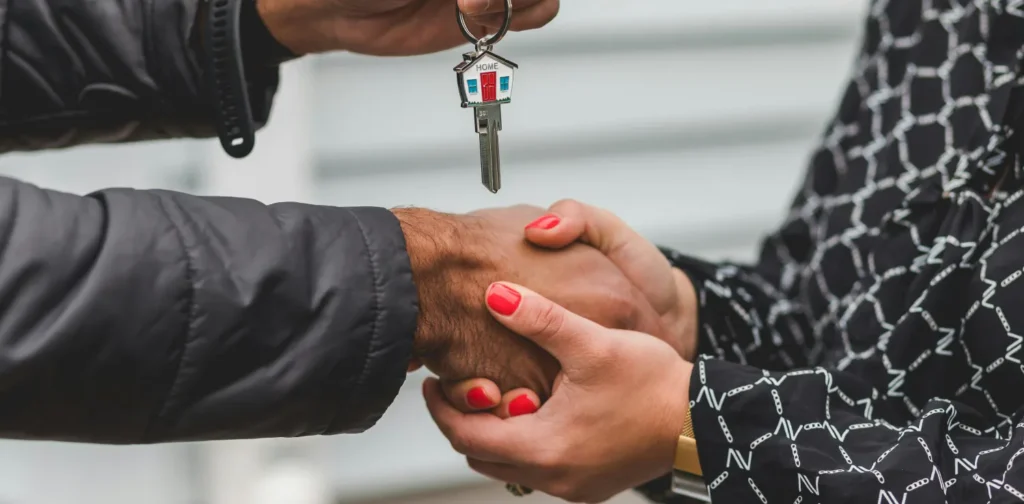 one person handing a house key over to another person