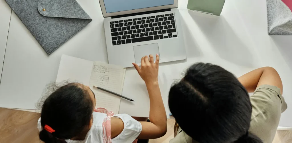 overhead view of a girl and her mother studying using laptop