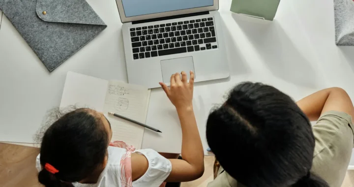 overhead view of a girl and her mother studying using laptop