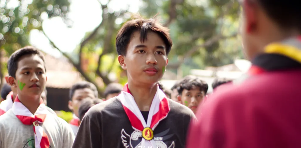 A group of adolescent boys in red and white ties standing face to face