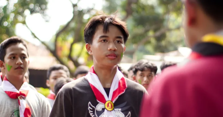 A group of adolescent boys in red and white ties standing face to face