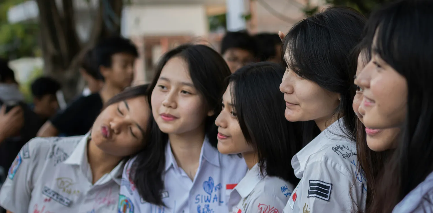 a group of girls wearing high school uniforms are taking photos together