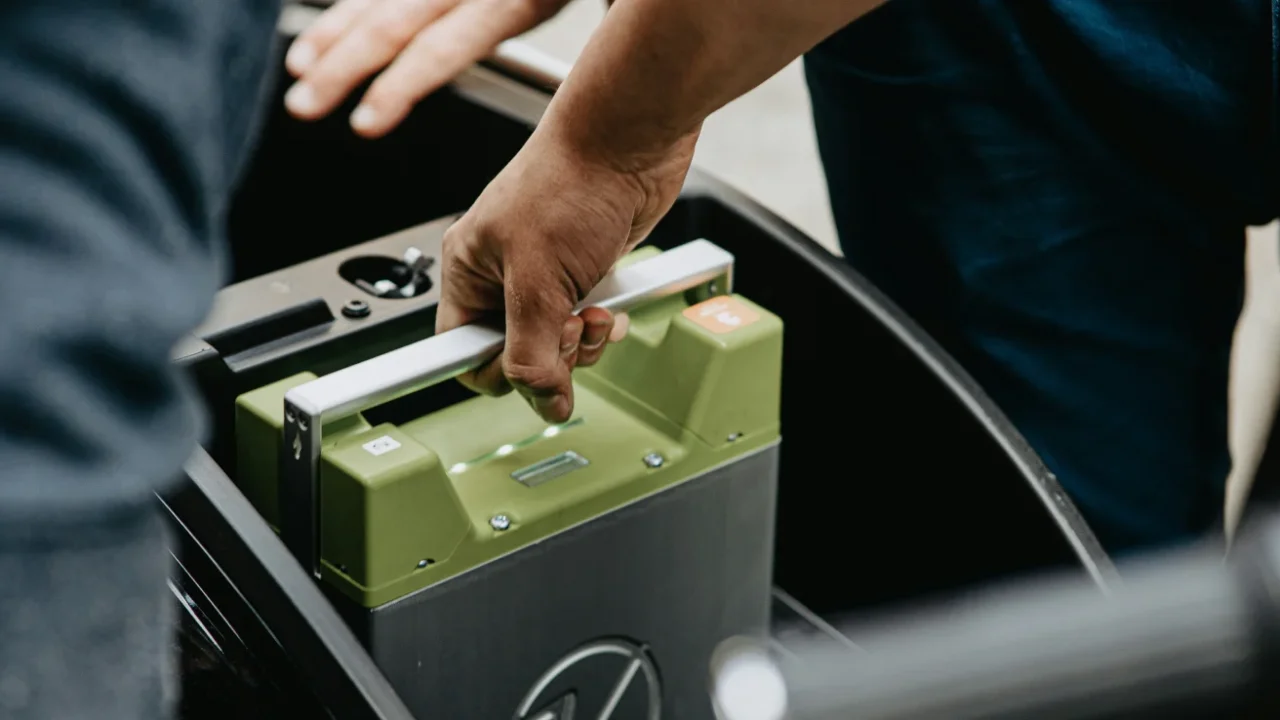 a hand holding a lithium battery inside an electric vehicle