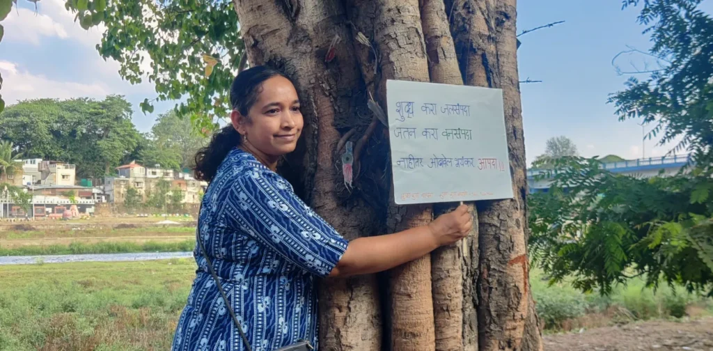 a woman hugging a tree holding a sign to protest deforestation in the Chipko Movement.