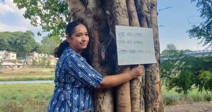 a woman hugging a tree holding a sign to protest deforestation in the Chipko Movement.