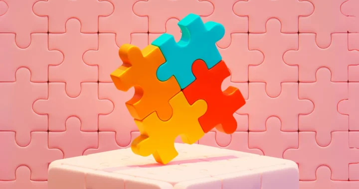 puzzle pieces in red, blue, orange, and yellow stacked on top of a pink block