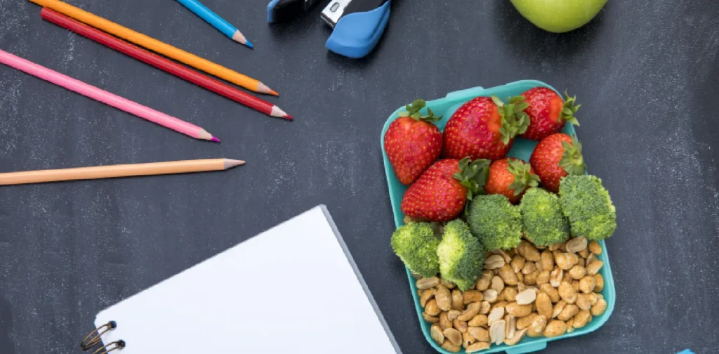 a photo of school lunch, a notebook, and stationary on top of a table
